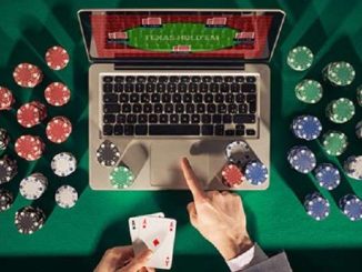 man playing online poker on a laptop computer with chips stacked around the table