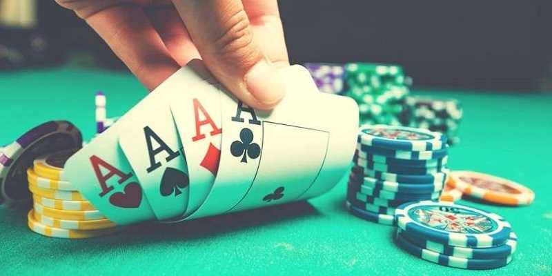 poker player showing four aces at table with poker chips