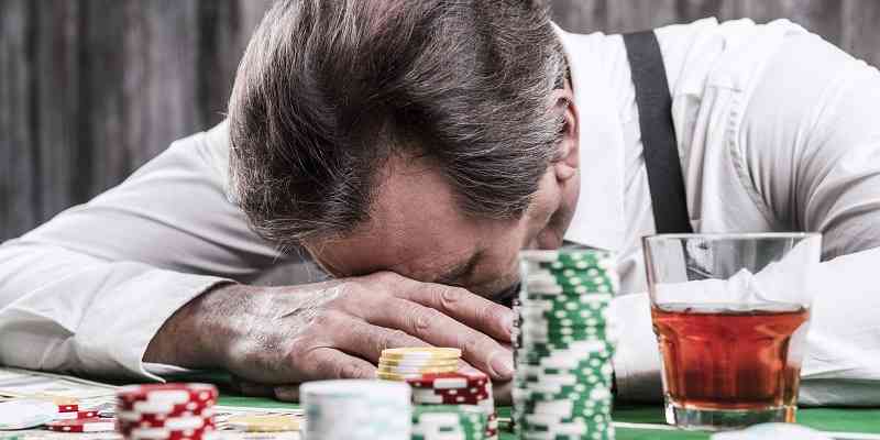 man with head in hands at poker table